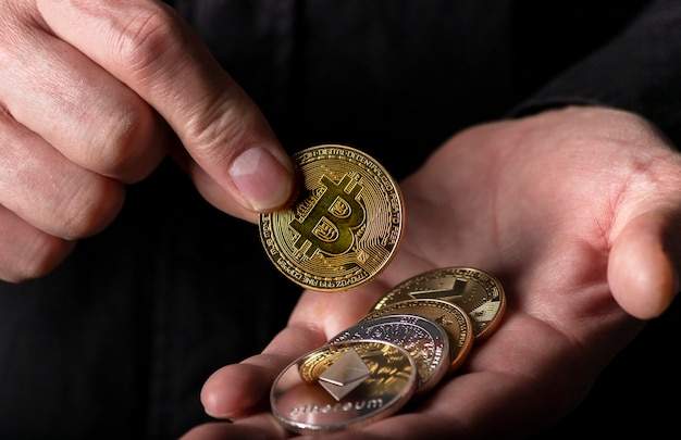 hand-putting-shiny-gold-bitcoin-into-palm-with-other-cryptocurrency-male-hand-black-background-close-up_361816-1503